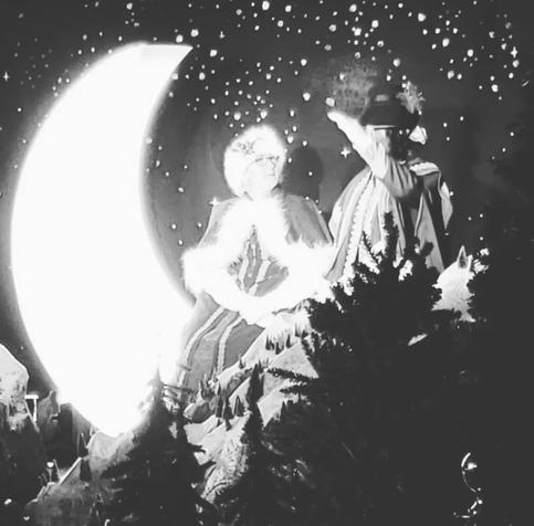 Mrs Clause sitting on a moon, talking with an elf. Black & White photo from Christmas 2 years ago