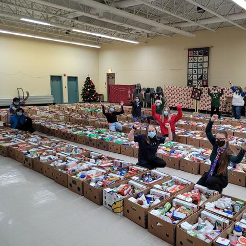 Group of youth arms raised in celebration among filled boxes of food