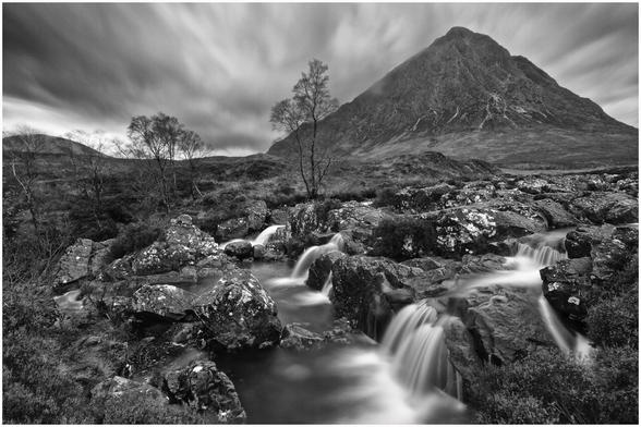 Triangular shaped mountain with stream in foreground. Monochrome.