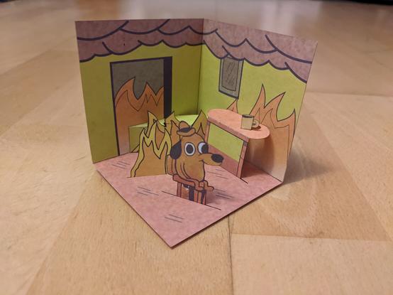 The scene from the "This is fine" meme, built as a diorama out of paper.