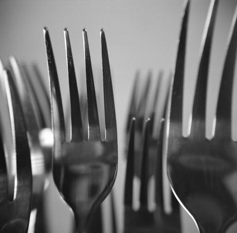 Black and white close up photograph of stainless steel forks.