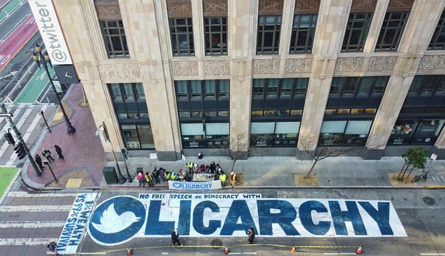 A picture taken from above shows a street mural painted in front of Twitter's San Francisco headquarters. The mural reads "No free speech or democracy with OLIGARCHY."