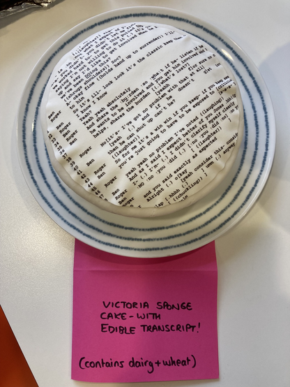 Picture of an iced cake. White icing, transcript of a conversation in courier font as Part of the icing.
