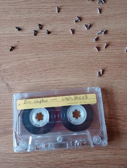 Eric Clapton on c90 on faux wood table surrounded by screws.