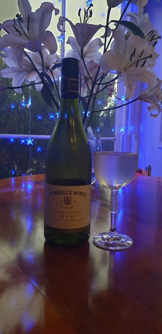 A bottle of Tyrrells HVD Semilllon with a glass, white lillies and blue Christmas lights