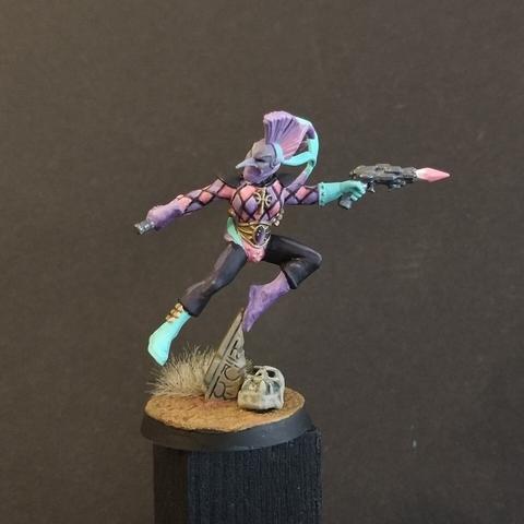 A miniature female aeldari harlquin for the warhammer 40k game. Painted with pink and purple check marks. A purple gem visible on the belt.