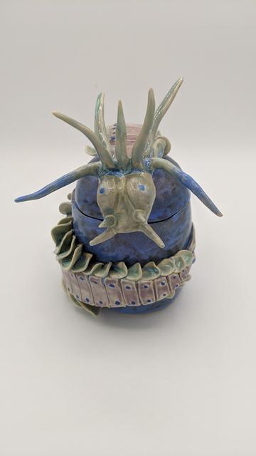 Pottery piece shaped like a segmented marine worm. The worm wraps around a rock-like shape.