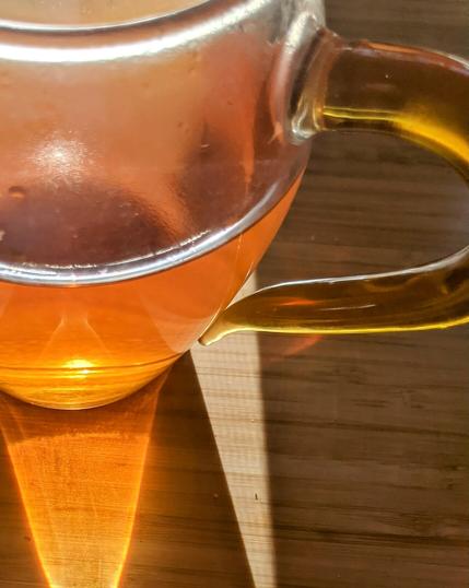 Black tea in a "fairness cup", sitting on desk, with sunlight illuminating