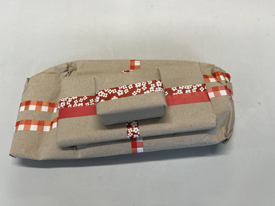 Three Secret Santa presents wrapped in brown paper and red&white Washi tape.