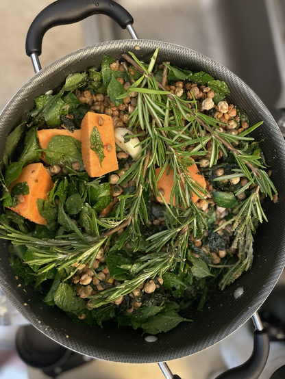 A pot of uncooked beans, sweet potato, rosemary, and Spanish Needle leaves