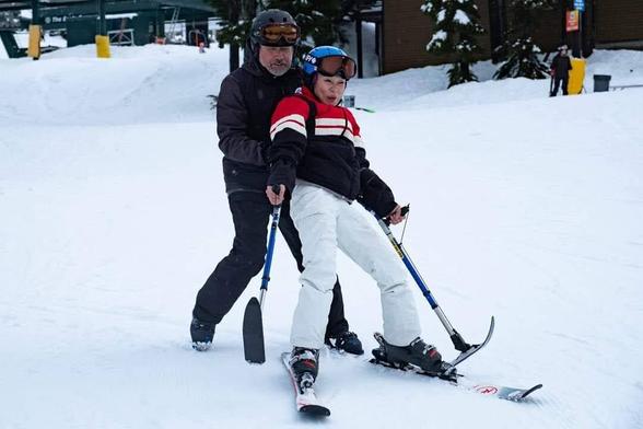 My adaptive ski instructor, catching me as I'm falling backwards on 4 track ski setup, on ski mountain.