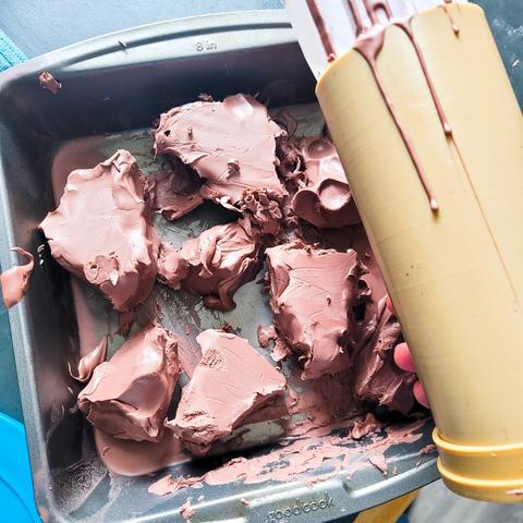 A pan of large clumps of browm monster clay are in a pan, headed for the oven. A cylinder mold is shown as well