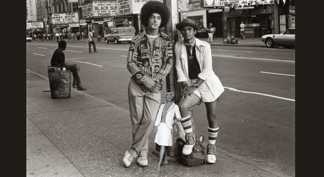 Photo of a two foot tall Doris Day standing next two young men in Times Square.