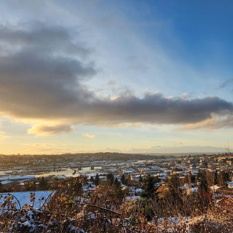 An overlook view of Ballard from Fremont Peak Park heading toward sunset, with some clouds in the distance, framing the view of the Olympic Mountains.