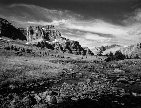Looking away from a small tarn in an alpine pass towards Noseeum peak and Dolomite peak in Banff National Park