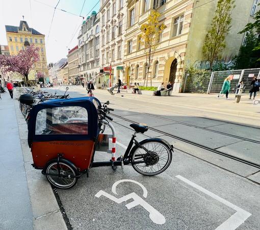 Radbügel reserviert für Behinderte mit dort abgestellten Lastenrad