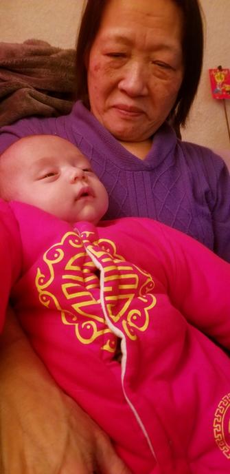 Baby Raven Sol, falling asleep in Grandma's arms.  Wearing his red Chinese plush outfit.
