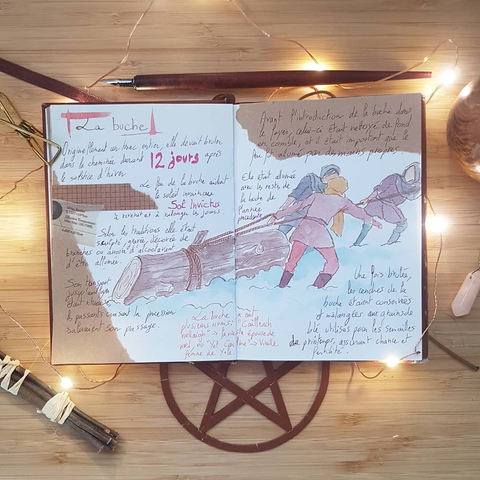 Carnet ouvert avec le dessin de personnages tirant une buche dans la neige avec des cordes. Autour du dessin des notes sur la buche :
Originellement un tronc entier, elle devait bruler dans la cheminée durant 12 jours après le solstice d'hiver.
Le feu de la buche aidait le soleil invaincu Sol Invictus a révenir et à rallonger les jours. 
Selon les traditions elle était sculptée, gravée, décorée de branches ou arrosée d'alcool avant d'être allumée. 
Son transport jusqu'au foyer était ritualisé, les passant croisant la procession saluaient son passage. 
La buche a eut plusieurs noms : "Cailleach hollaigh" > La vieille épouse de noel, ou "Yel Carline" > Vieille femme de Yule.
Avant l'introduction de la buche dans le foyer, celui-ci était nettoyé de fond en comble, et il était important que le feu fut allumé par des mains propres.
Elle était allumée avec les restes de la buche de l'année précédente. 
Une fois brulée, les cendres de la buche étaient conservées et mélangés aux grains de blé utilisés pour les semailles du printemps, assurant chance et fertilité