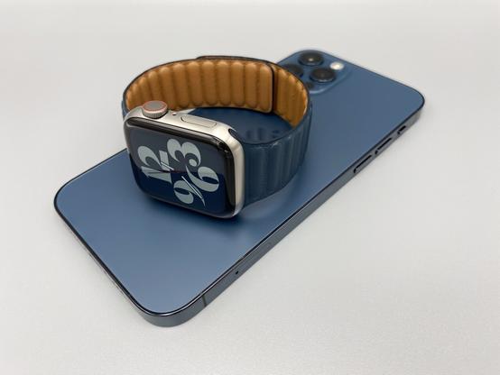 Baltic Blue Leather Link with Apple Watch Series 6 Edition (Titanium) laying on iPhone 12 Pro Pacific Blue, on a neutral gray background