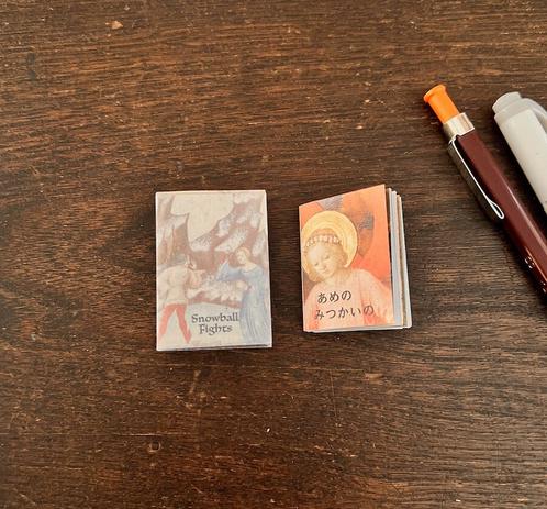 Two miniature books on a wooden desk.