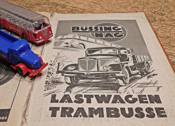 Zwei alte Wiking-Modelle, ein Büssing Trambus und ein Büssing LKW, stehen auf einer alten Büssing-Werbung in einem alten Straßen-Atlas. Die Werbung zeigt schwarz-weiße Zeichnungen eines Büssing Trambus und eines Büssing LKW.
Als Untergrund dient eine alte Landkarte.