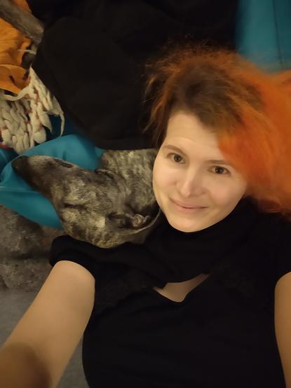 Lara liegt auf dem Boden und nutzt das Hundebett als Kopfkissen, Sloughi Sarai hat ihren weichen Hals gegen Laras Kopf geschmiegt und schlummert friedlich. Sarai wird von Laras Pullover zugedeckt.