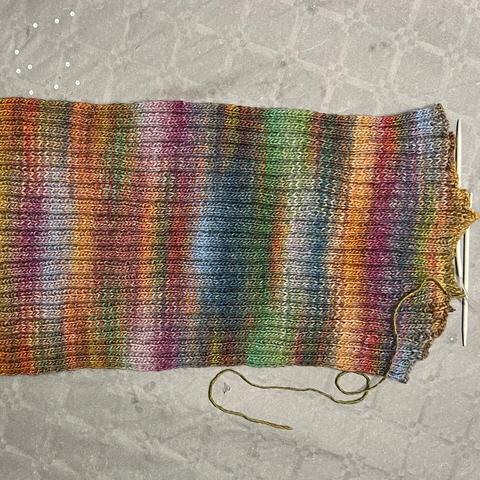 A piece of multicoloured knitting - the back of a jumper, knitted in 3,3 rib