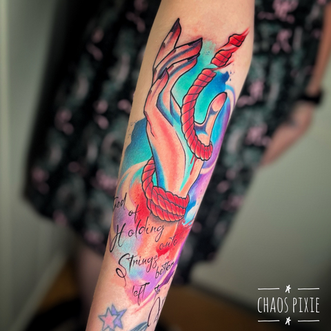 Hand tied up by a rope on the wrist, letting the rope go so it frees itself. With the lyrics "tired of holding onto strings better left to fray" underneath and watercolour as background