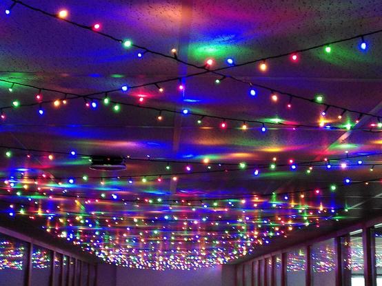 Bunte kleine "Sterne"-Lichterkette leuchten von der Decke in einem dunklen Raum.