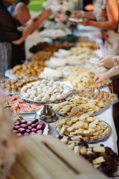 A long banquet table filled with trays and trays of small cookies of all types