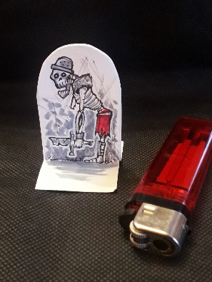 Paper miniature of a silly looking skeleton.  Standard cigarette lighter for scale.