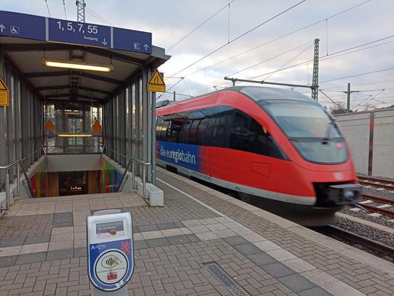 Ein Dieseltriebzug des Typs Bombardier Talent fährt von einem Bahnsteig ab, an dem ein OV-chipkaart-paaltje von Arriva steht