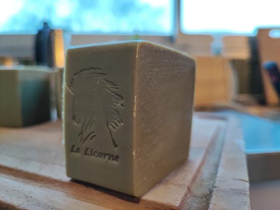 Une tranche de savon verdâtre, moulé sur le savon une tête de licorne et le texte "La Licorne"