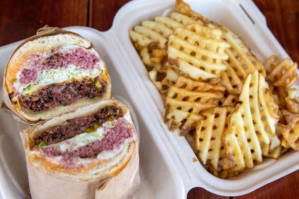 The Allison, with pastrami and roast beef, served with a side of waffle fries, is one of the signature sandwiches at Deli Board in San Francisco, Calif. on Aug. 19, 2022.