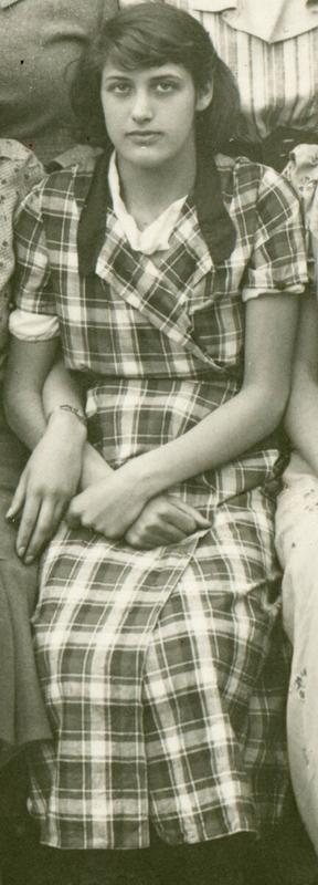 A girl sitting in a checked dress.