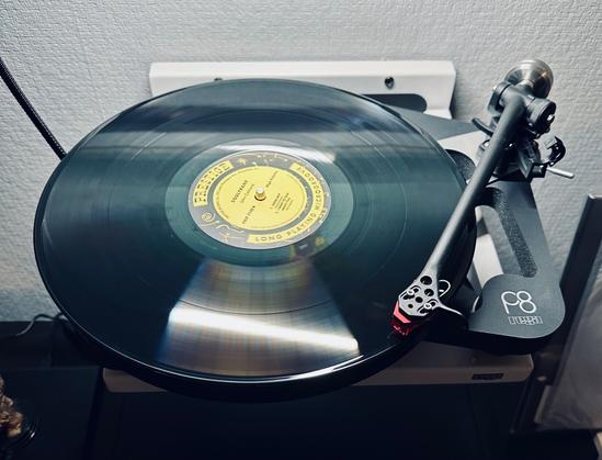 A photo of a record spinning on the skeletal plinth of a Rega P8. 

The centre label is yellow and black. Black lettering reading, Soultrane, is just visible above the spindle. The lettering, Song Playing Microgroove, arcs along the bottom of the label. 

The tone arm, a hint of red cartridge, traces the first track of the album.