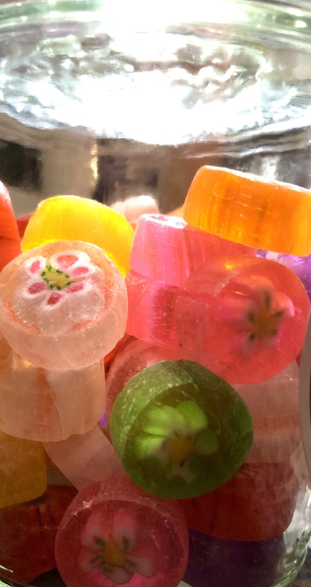 A close up view of the colorful, translucent candies. Here the little flower shapes are clearer and the sugary dust on some of the candies is easier to observe.
