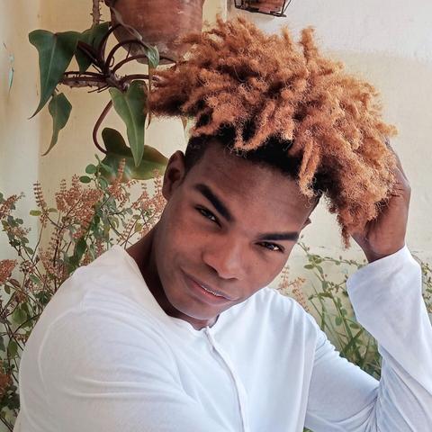 Foto de un muchacho sonriente, con pelo afro, mirando a cámara.
