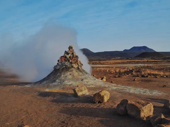 A steamy fumarole in a geothermal area with an otherworldly landscape.