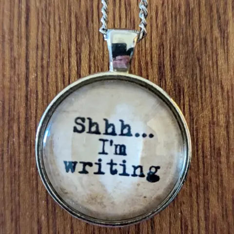 Necklace with 'shhh... I'm writing ' on it.