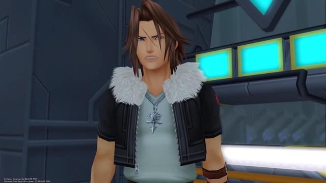 A shot of Leon from the waist of as he grimaces in response to Sora. He has long brown hair that comes down in front of his face, a scar between the eyes, a leather jacket with fluffy white collar, and a white tshirt underneath and his iconic Lionheart necklace.
