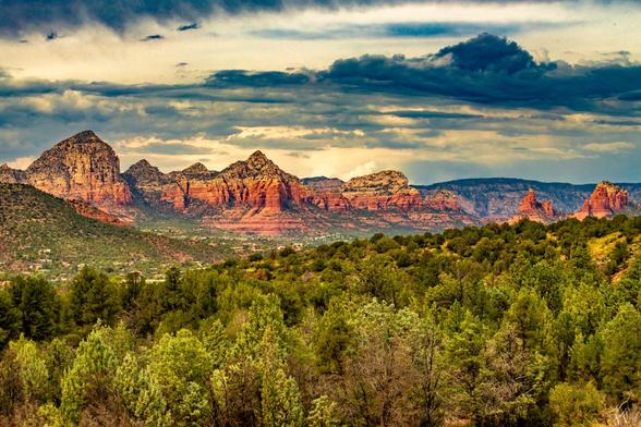 Sedona 10232

How do you describe this beautiful area tucked in North Central Arizona not too far south of the Grand Canyon.
In this case, I think a picture speaks thousands of words. You could forever try to describe the beautiful rock formations but I'm nit sure that words are adequate.
I have been especially blessed as both times now, that I have been to Sedona, I have had a canopy of clouds overhead creating a fantastic light interplay that is displayed on the face of these beautiful red cliffs of sandstone.
This image was captured in the vicinity of the Broken Arrow Trail. The broken area trail takes you out to Submarine Rock, The Hogs, Twin Buttes, the crimson curtain and other features.
I was able to catch this image as a storm threatened, as it continued for the afternoon.
In further detail, this image looks across a valley with red and brown cliffs and towering buttes in the distance. In between my location and the distant buttes are smaller trees and desert scrub as far as the eye can see.