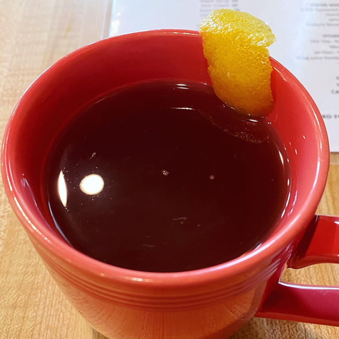 Hot toddy in a salmon-colored mug with lemon rind sliver