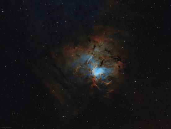 Colourful nebula with a blue core and a dusty red outer shell, surrounded by stars