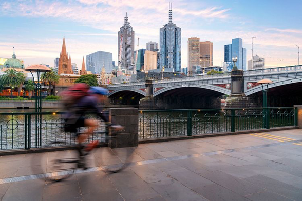Person on bike riding on bike-lane next to river in city
