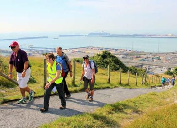 Group of walkers walking up a road with Dover in the background