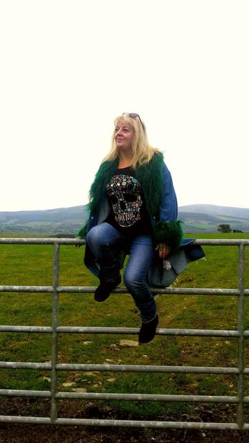 A woman sitting on top of a 5 barred gate in the Dublin mountains