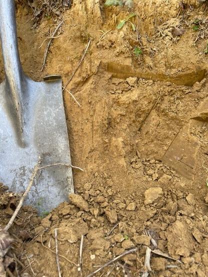 Outcrop of deep soil profile developed in yellowish tan colored #tuff.  Small shovel head adjacent to freshly exposed deep compacted soil.