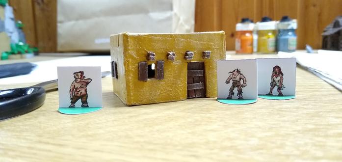 small paper miniatures of zombies and a cardboard house