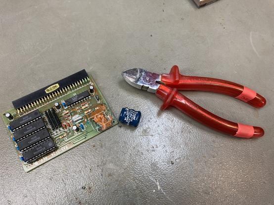 An Amiga 500 RAM Expansion with some corrosion on the PCB, a leaked Varta rechargeable battery that got removed from it and a pair of side cutters. All sitting on my workbench.